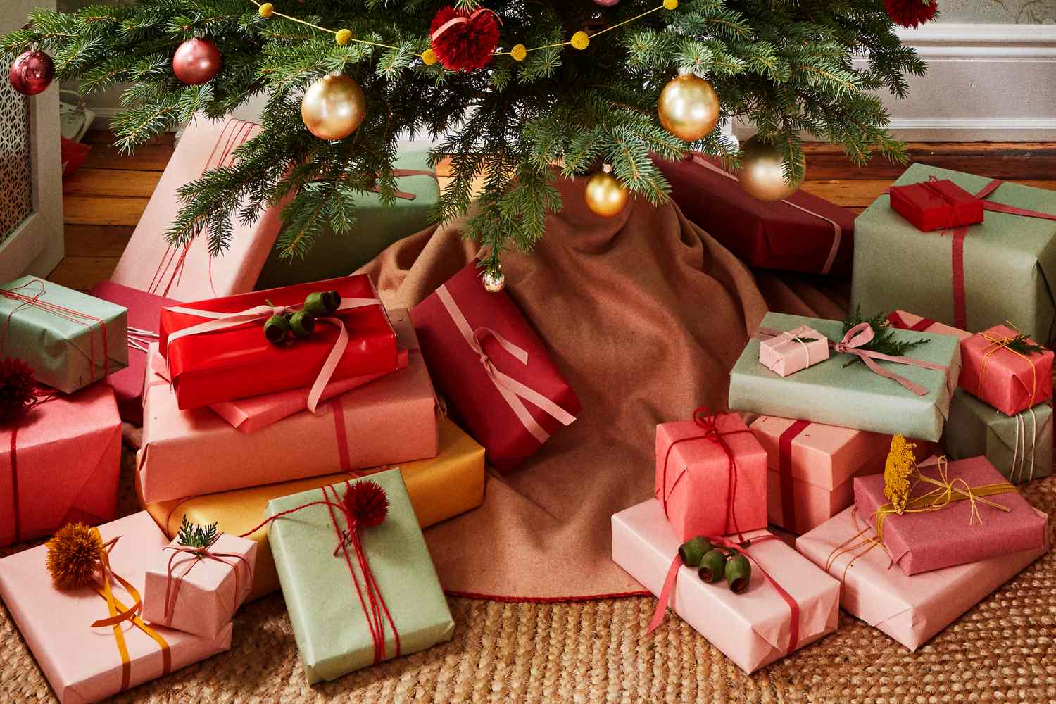 Various wrapped gifts arranged under a decorated Christmas tree with ornaments