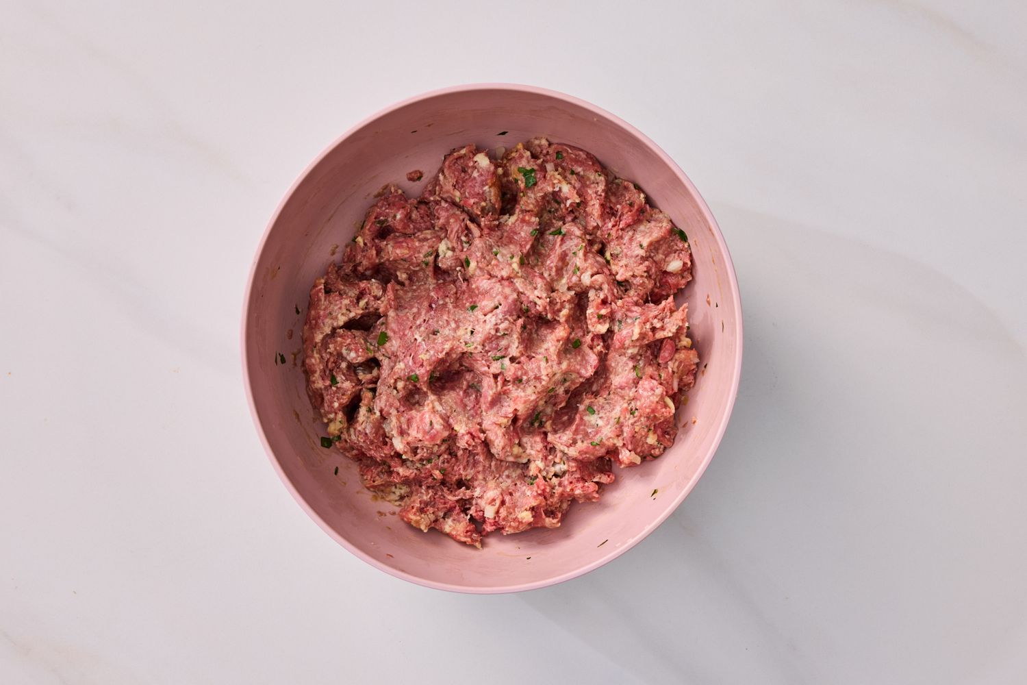 Raw ground meat mixture with seasoning in a bowl