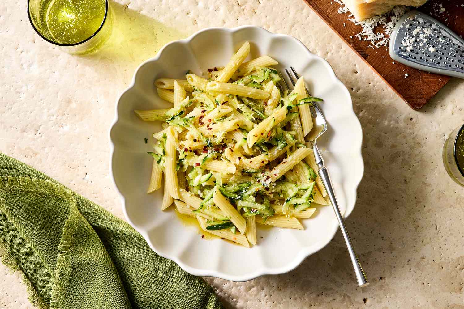 A plate of penne pasta with zucchini and grated cheese