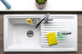 An overhead shot of a clean kitchen sink, a sponge and washing up liquid can be seen near by.