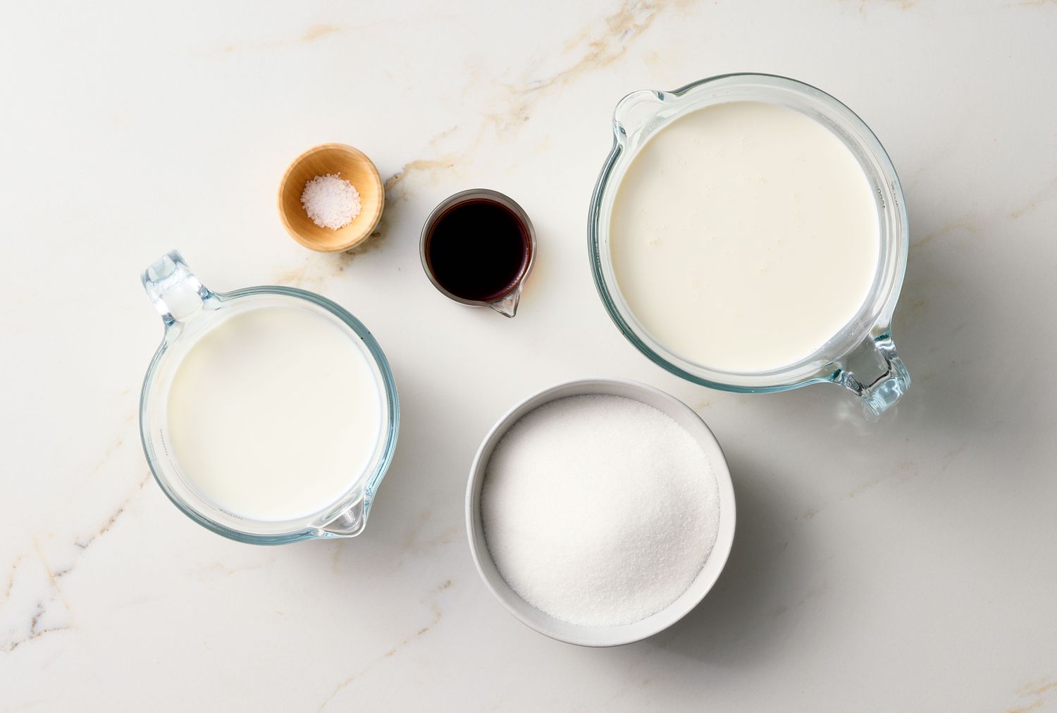 Ingredients including cream, milk, sugar, vanilla, and salt are arranged on a surface