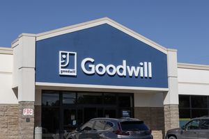 The exterior of a Goodwill store entrance with cars parked in front