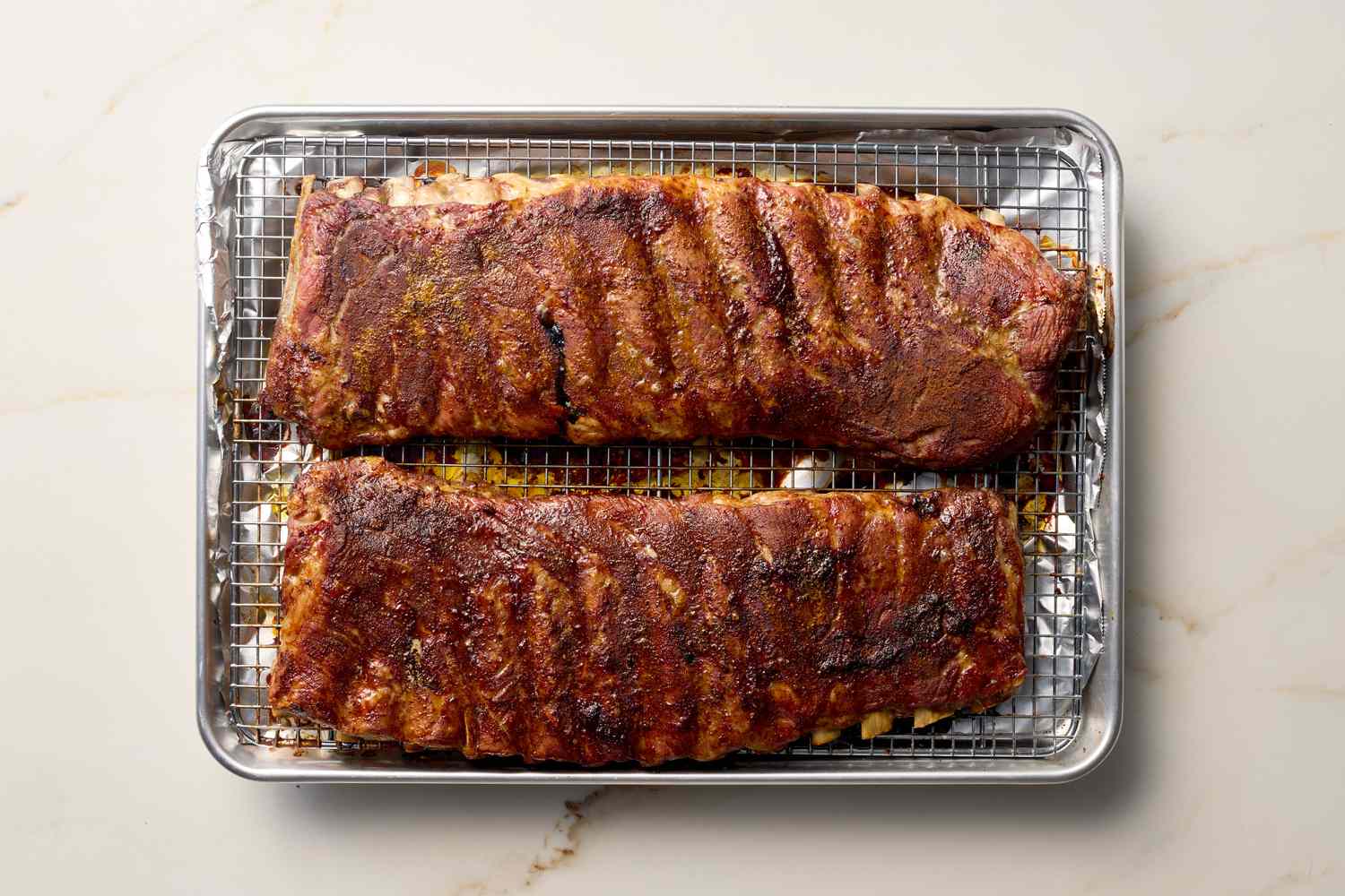 Two racks of oven-roasted ribs on a wire rack over a baking sheet