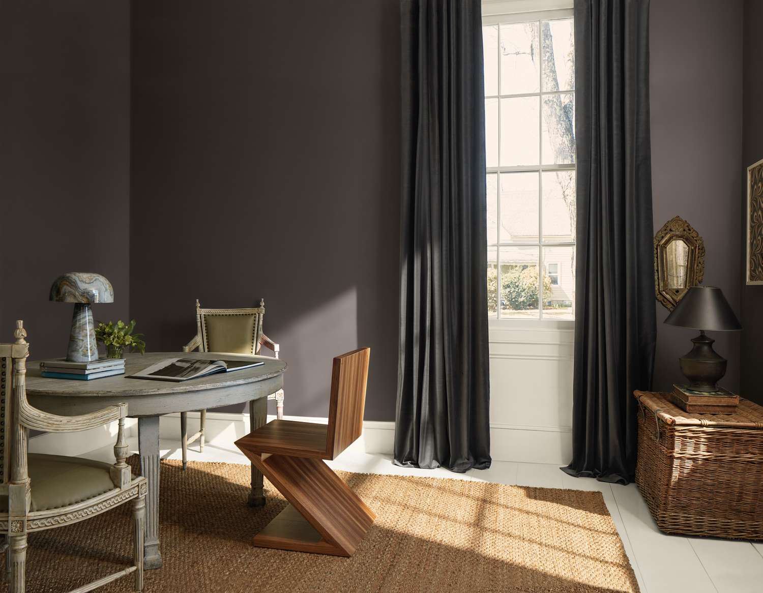 A furnished interior space featuring a table chair and window with draped curtains