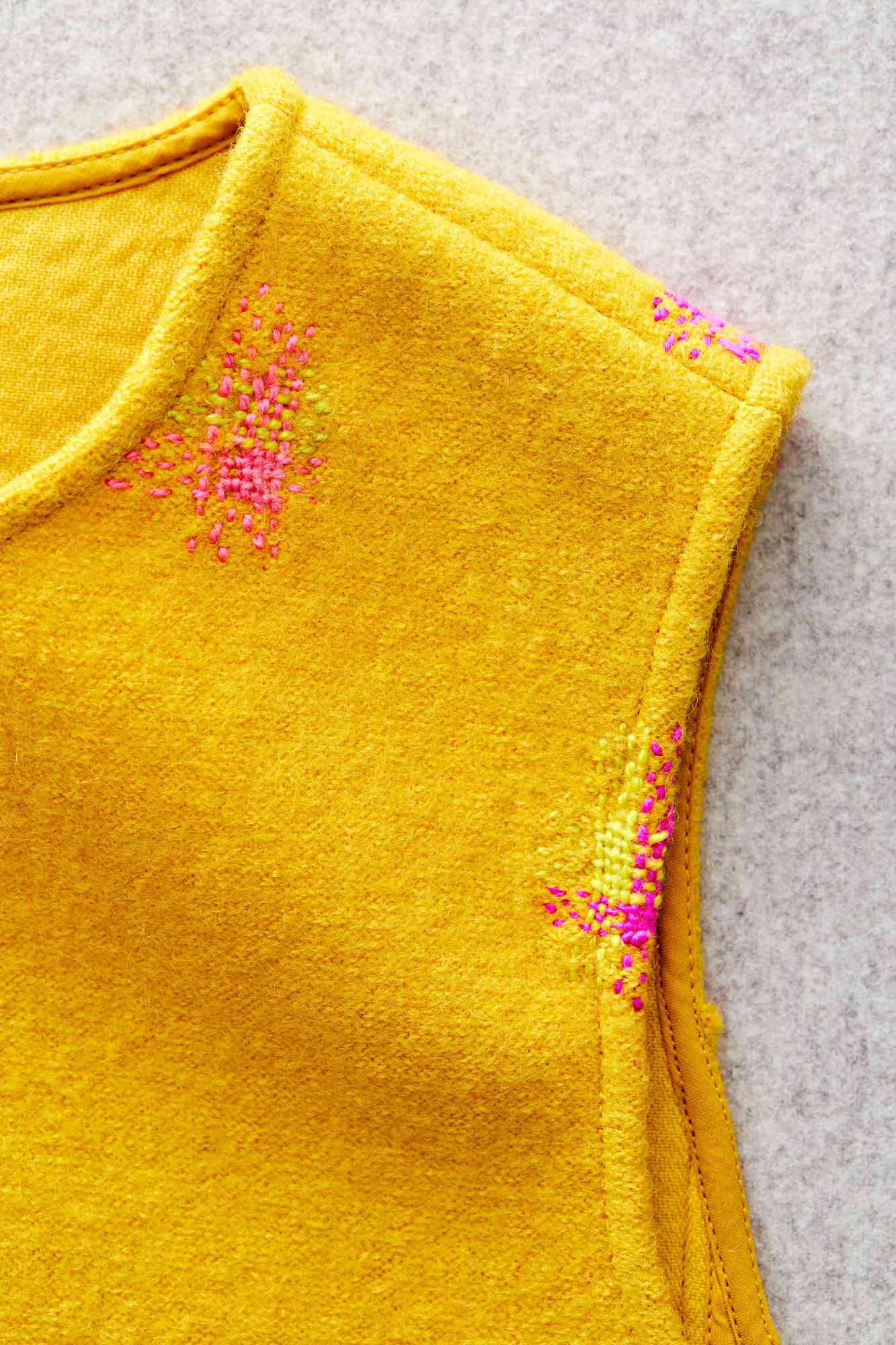 a mended sweater vest with pink thread