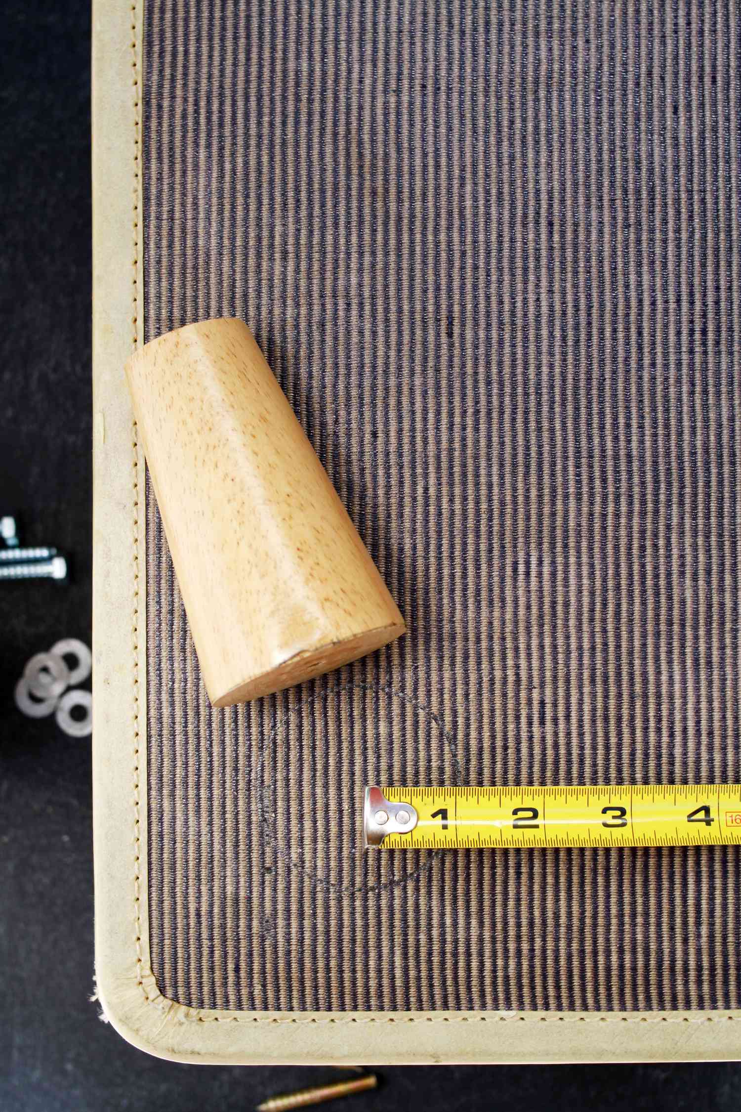 Suitcase with a chair leg and measuring tape on top of it