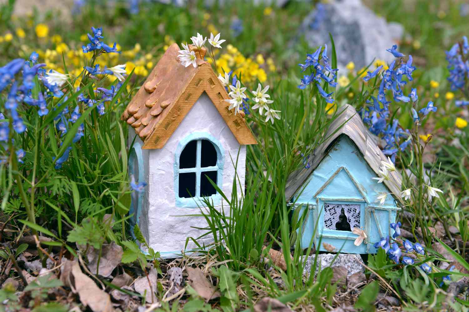 Two tiny fairy houses in spring flowers. Greeting cards, birthday, love and romantic concept. Vintage summer background