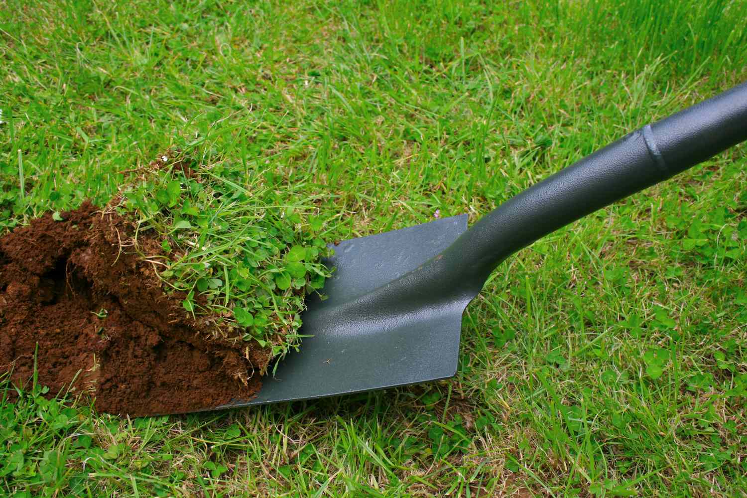 A shovel digging into grass and soil
