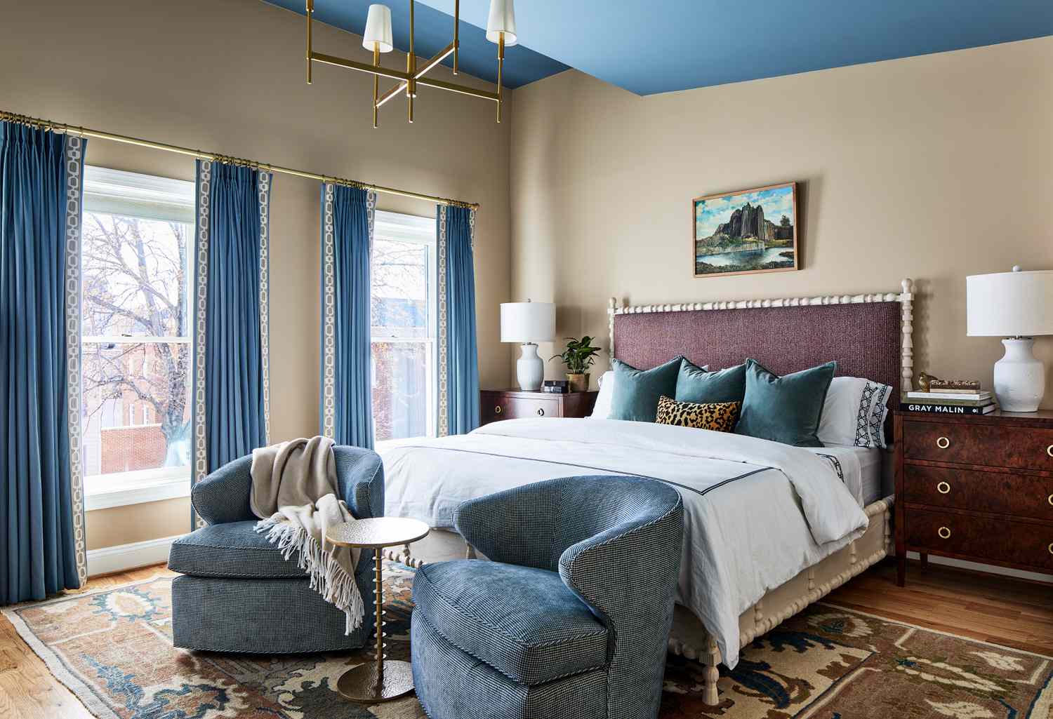 a neutral bedroom with blue chairs and curtains