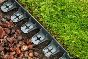 A closeup of a garden edging separating decorative stones from a grass lawn