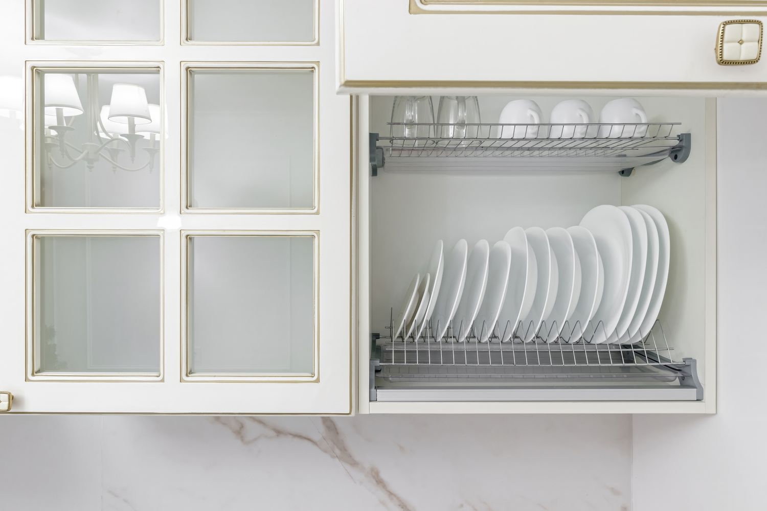 A kitchen cabinet with an open dish drying rack holding plates and cups