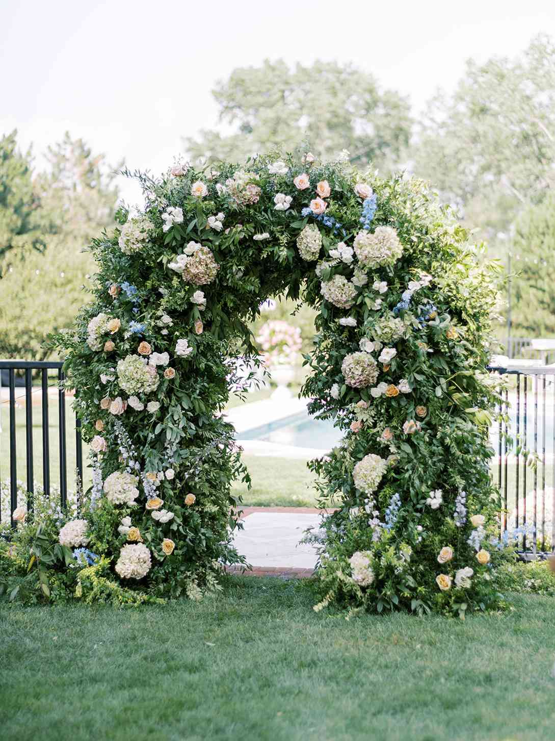 white and blue floral greenery covered archway