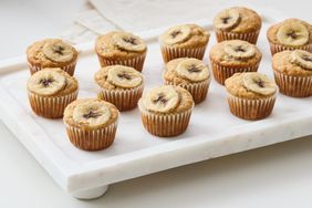 Banana muffins on a marble tray topped with banana slices