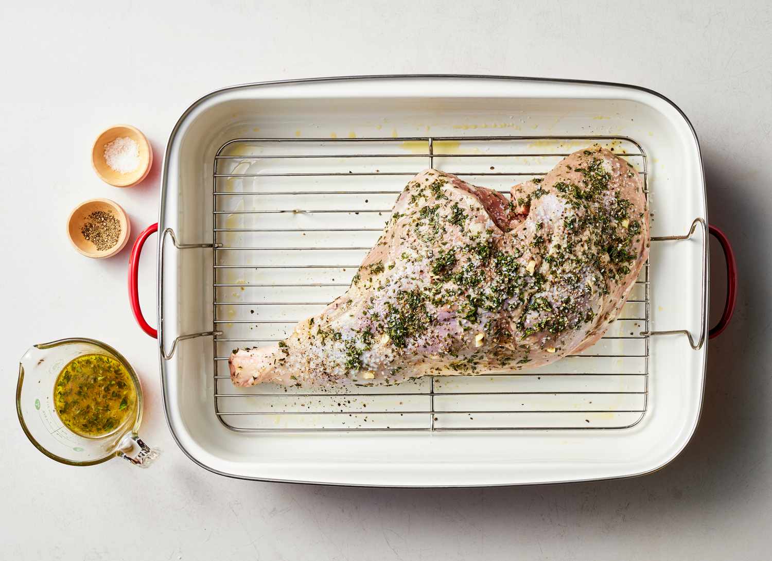 raw leg of lamb with herb mixture in a roasting pan