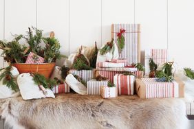 Gift boxes wrapped with striped paper and decorated with greenery arranged on a soft fur surface