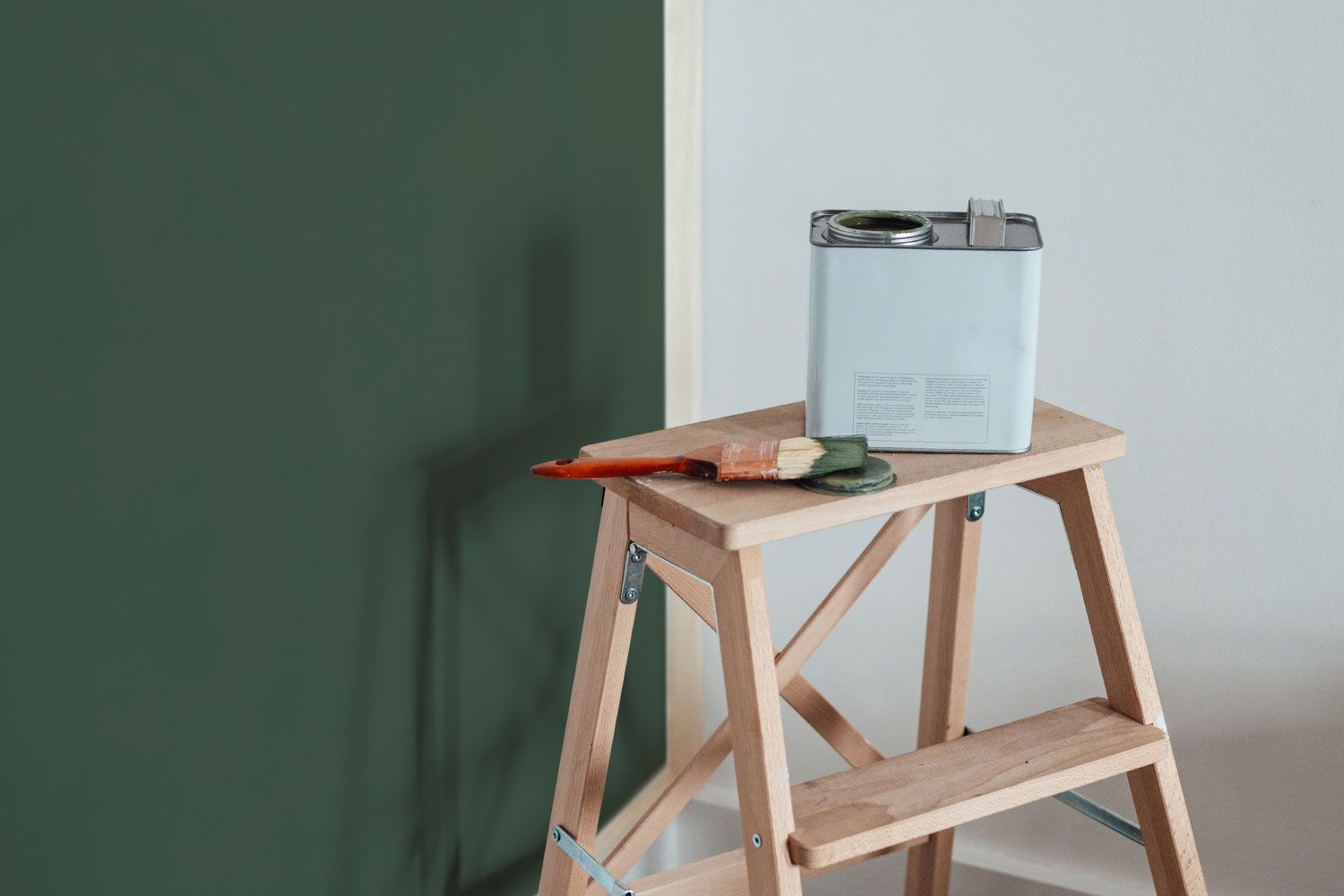 Wall painted green with stool and paint can and brush