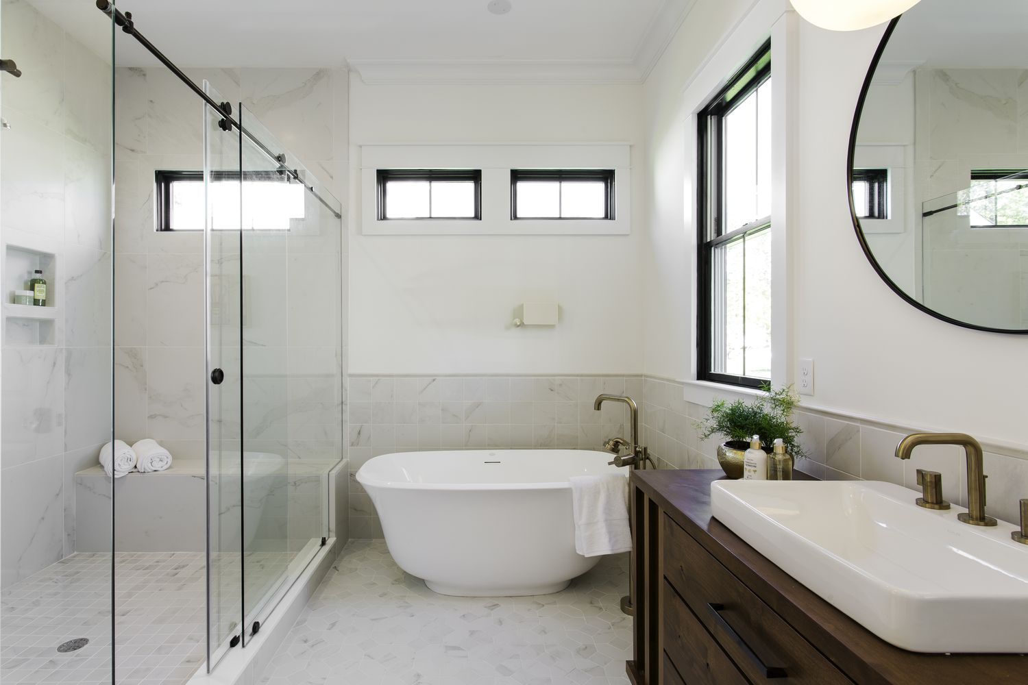 Modern bathroom with a freestanding bathtub glass shower enclosure and a vanity with a round mirror