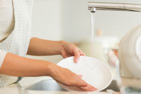 Person rinsing a plate under running water in a sink