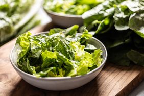 torn romaine lettuce in a white bowl on a wooden board