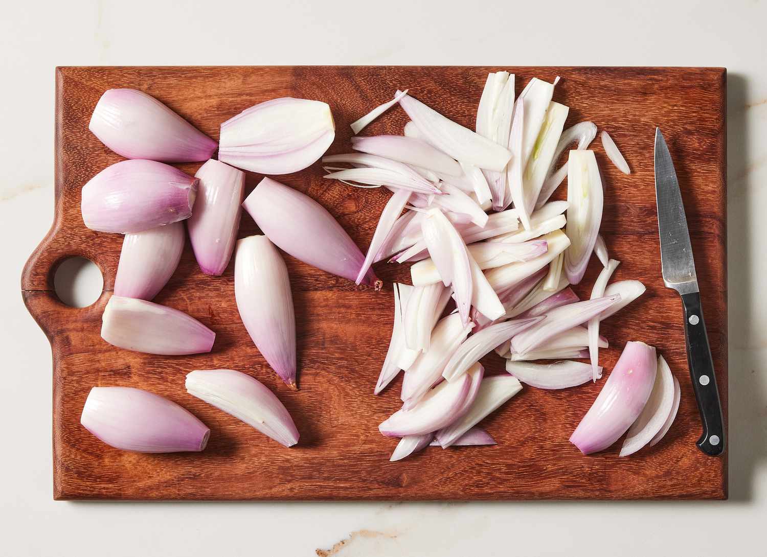 overhead view of whole and sliced shallots on a cutting board