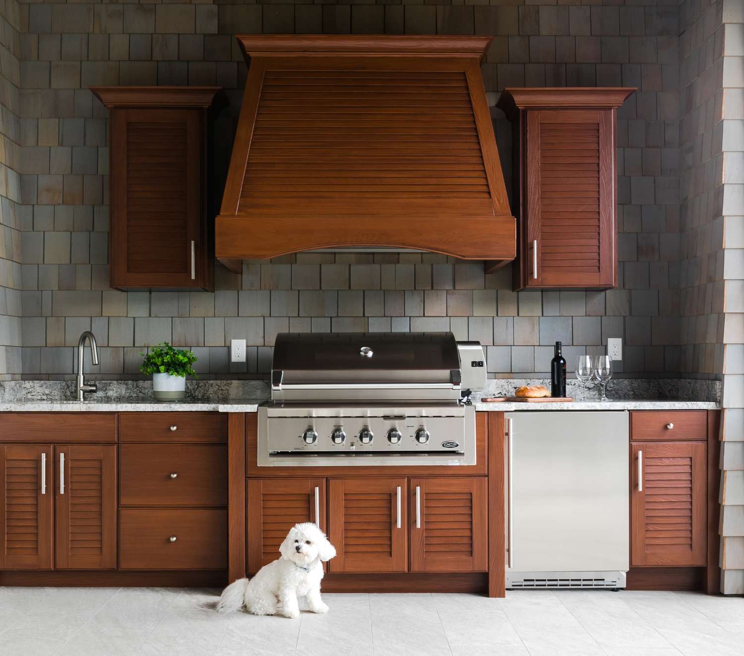 outdoor kitchen of a shingled house made with dark wood cabinetry