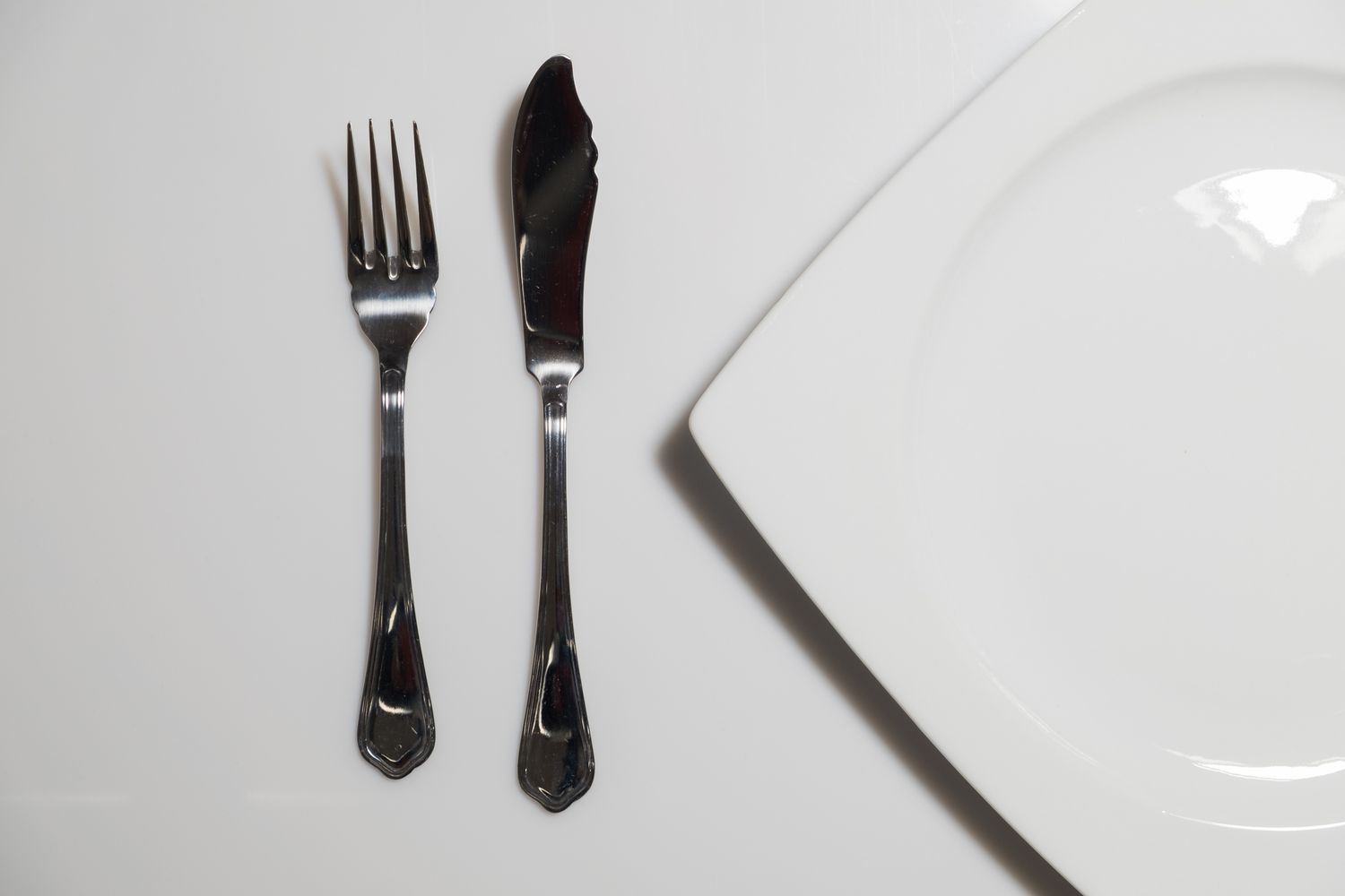 Fork and fish knife beside a plate on a table