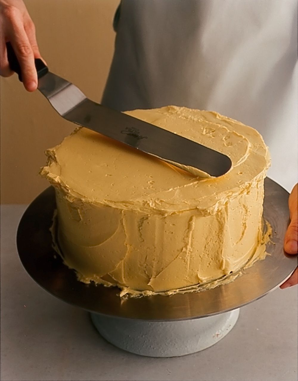 Smoothing frosting on layer cake