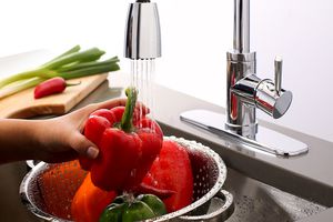Woman washing peppers under a vegetable sprayer