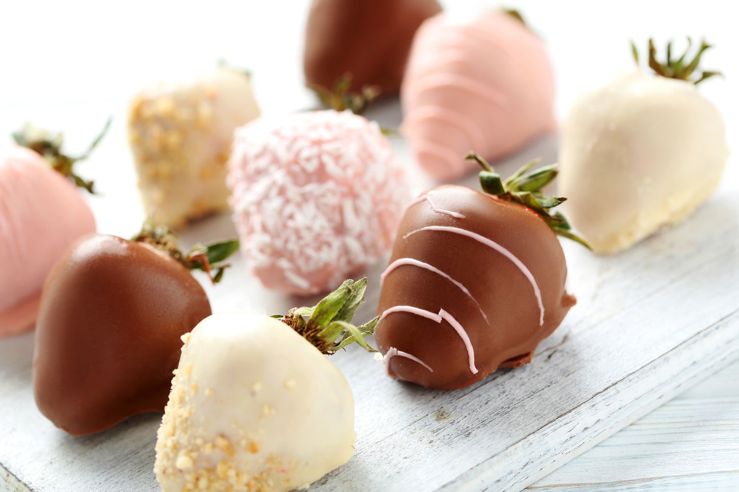Strawberries covered in chocolate on a white wooden table