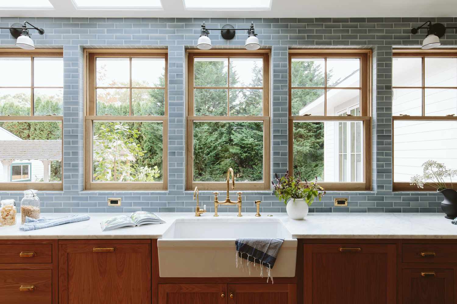 A kitchen interior with a farmhouse sink wooden cabinets and windows overlooking a garden