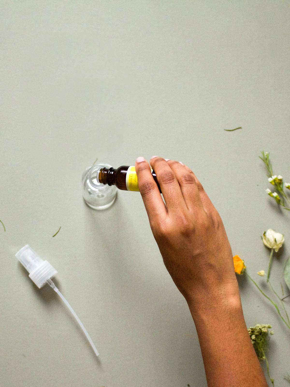Person pouring essential oils into a spray bottle. 