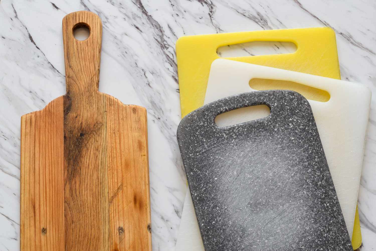 Side by side view of wooden and plastic cutting boards. Concept of kitchen choice, hygiene, food safety, sustainability, and household preferences