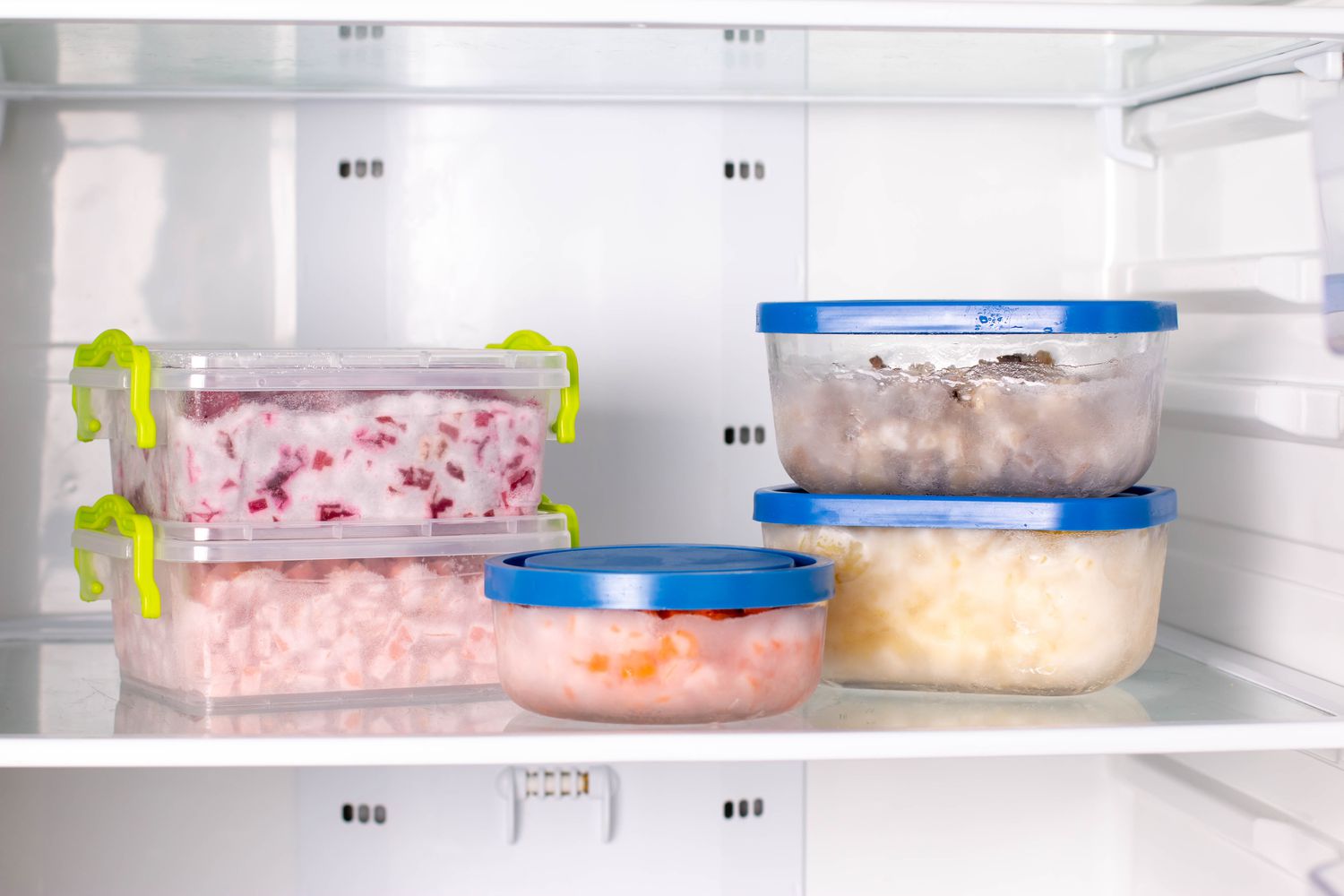Plastic containers with different frozen vegetables in refrigerator.