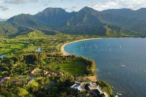 Aerial view of a coastal area with a bay small boats and a backdrop of mountains and greenery