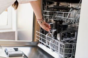 close up of woman unloading a clean dishwasher