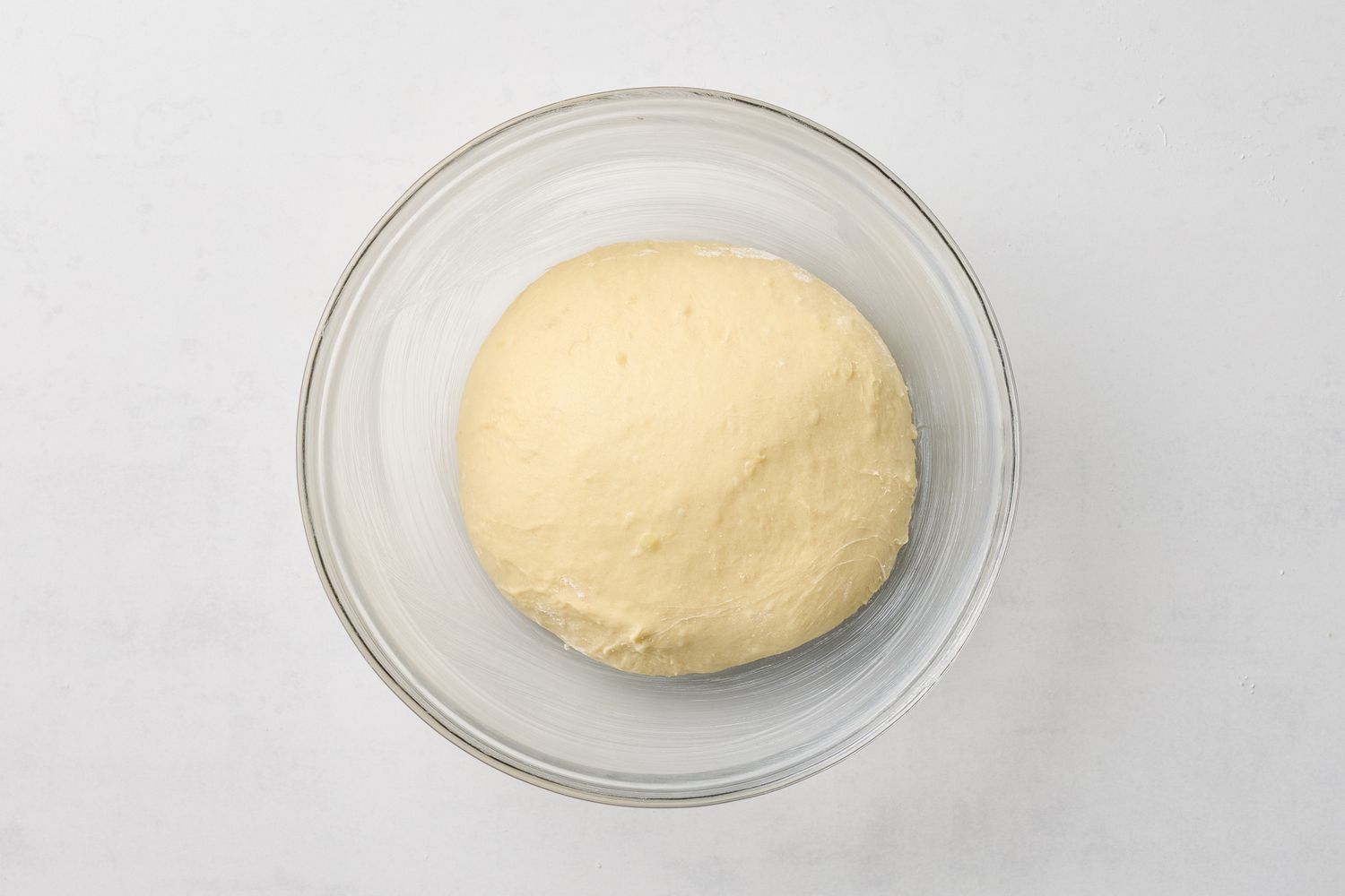 A ball of dough in a clear glass bowl
