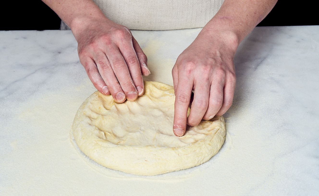 person kneading pizza dough