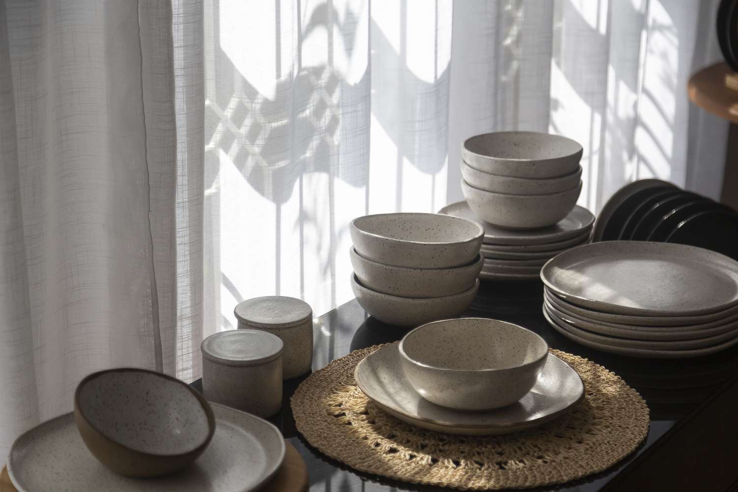 Tableware arranged on a table in front of a window with light streaming in