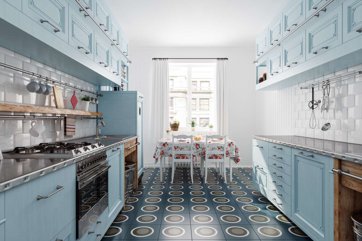 A kitchen with blue cabinets a dining table with a floral tablecloth and a window in the background