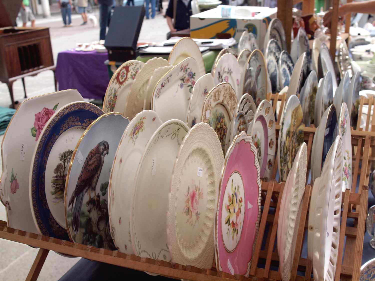 A display of decorative plates on a wooden rack at a market stall