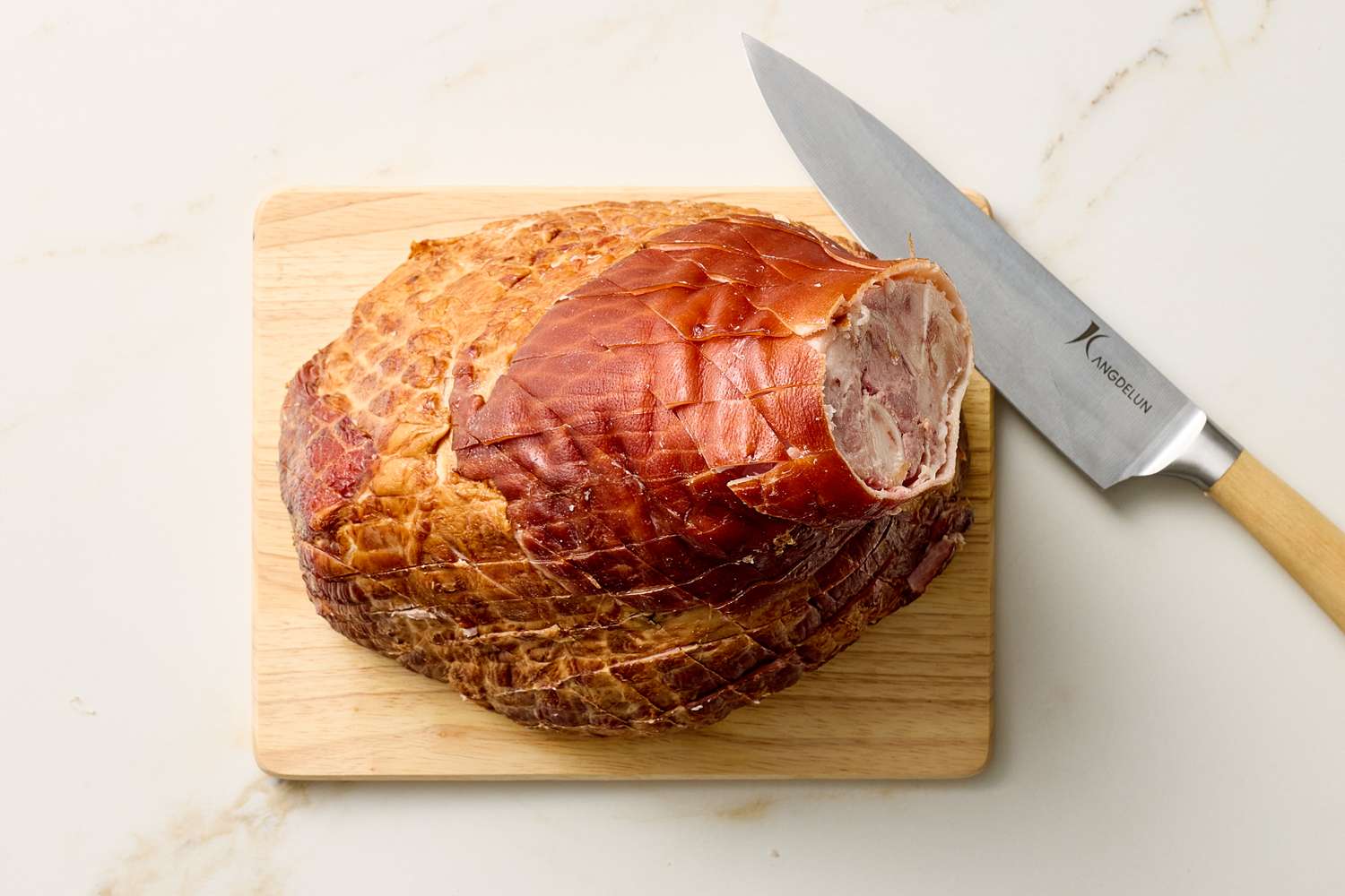 Sliced cooked ham on a cutting board with a knife on the side