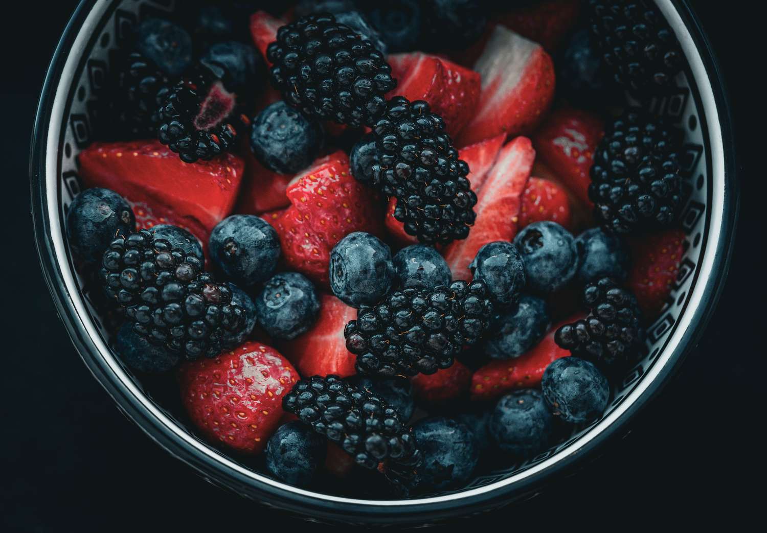 A bowl filled with strawberries blackberries and blueberries