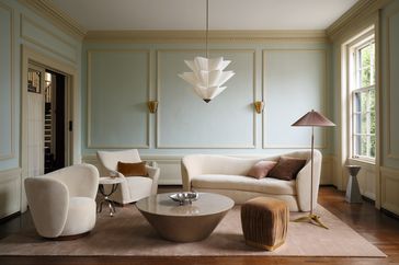 A modern living room with minimalist furniture including sofas chairs a coffee table and wallmounted lights