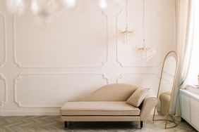 Elegant room with a chaise lounge, standing gold mirror, and chandeliers