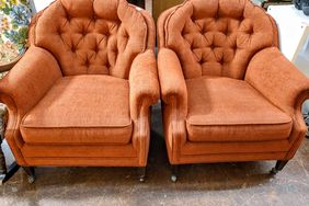 Two tufted armchairs with cushioned seats on a wooden floor