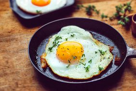 A fried egg garnished with herbs in a skillet