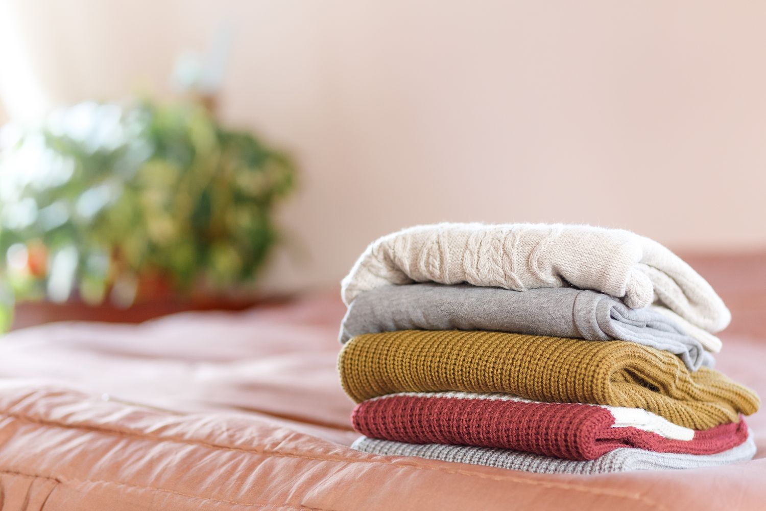 clean sweaters after washing,stacks of clean knitted clothes at home on bed Concept of cozy home and house work. Cope space