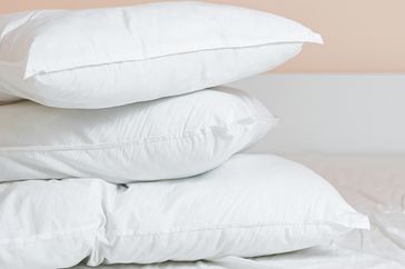 Three stacked pillows on a bed