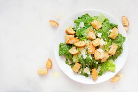 Caesar salad topped with croutons and cheese on a white plate