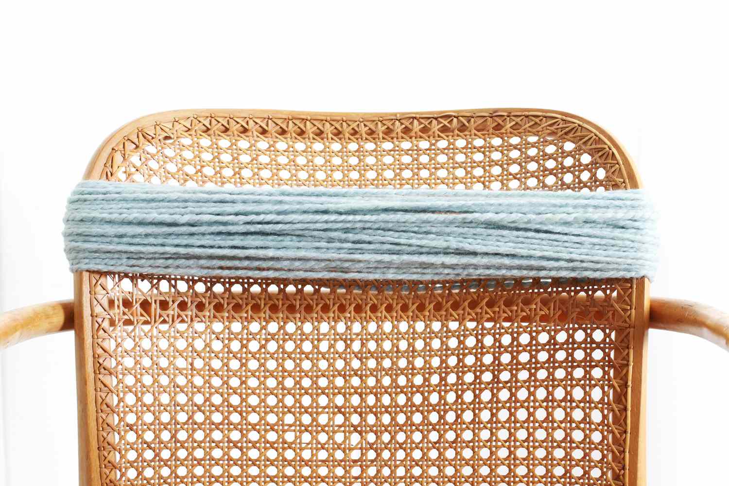 blue yarn wrapped around back of wicker chair